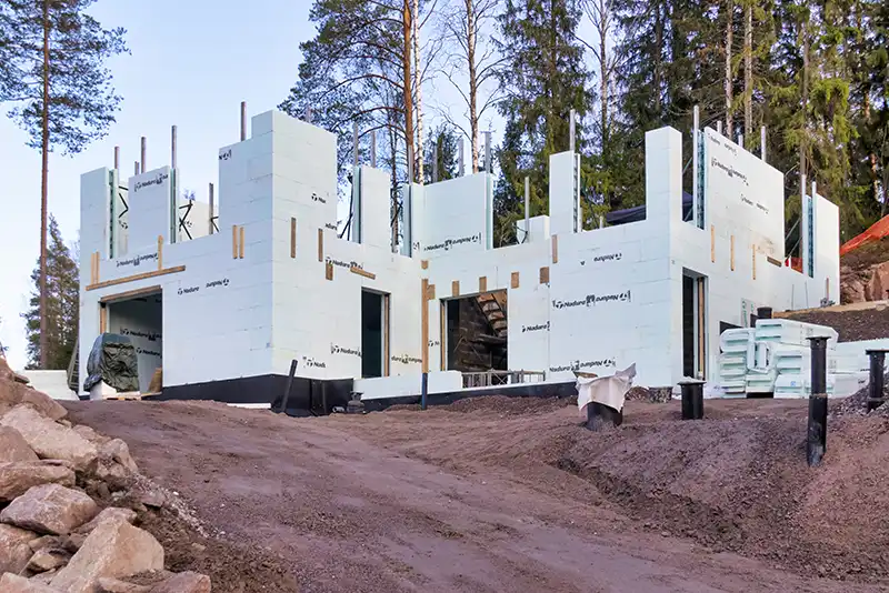 Kivitalon ja autotallin Nudura-runko nousemassa metsätontilla Espoossa
